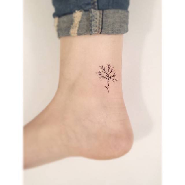 Name and leafless tree tattoo located on the ankle.