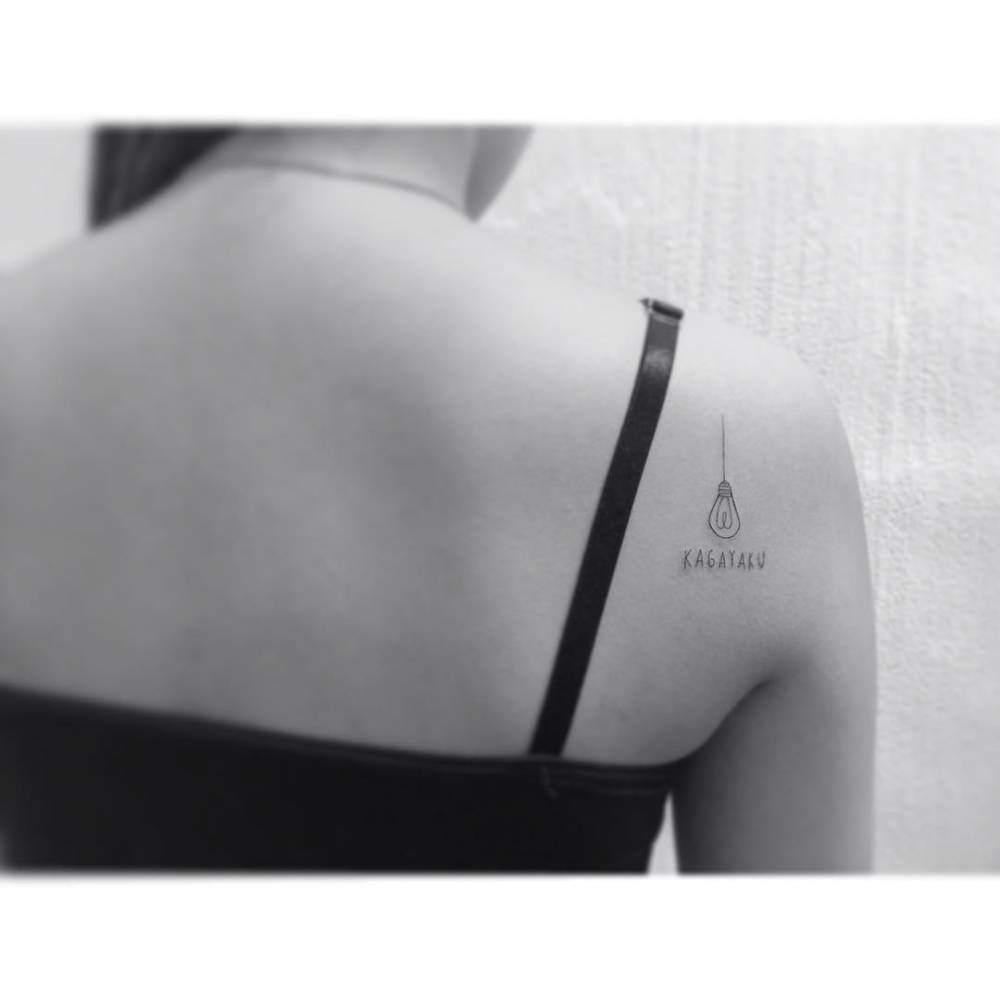 Light bulb and word "kagayaku" tattooed on the shoulder blade.