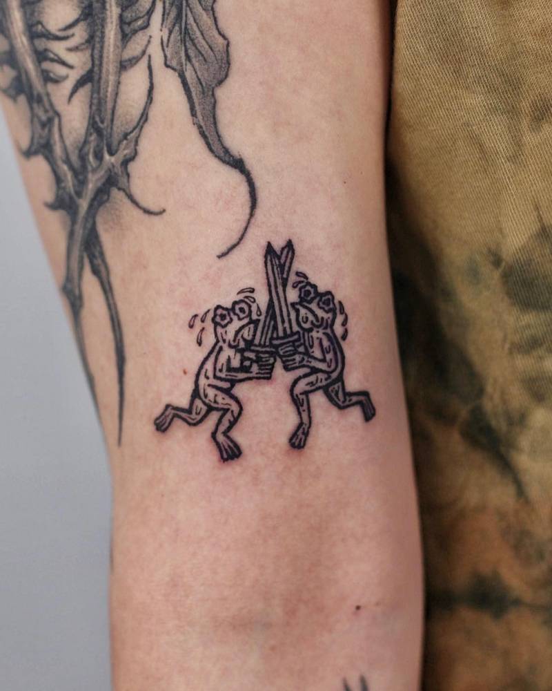 Frog battle royale tattoo located on the bicep.