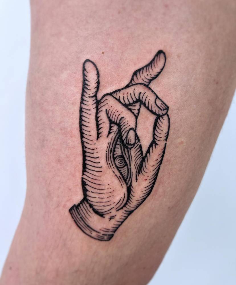 Engraving style hand tattoo located on the inner arm.