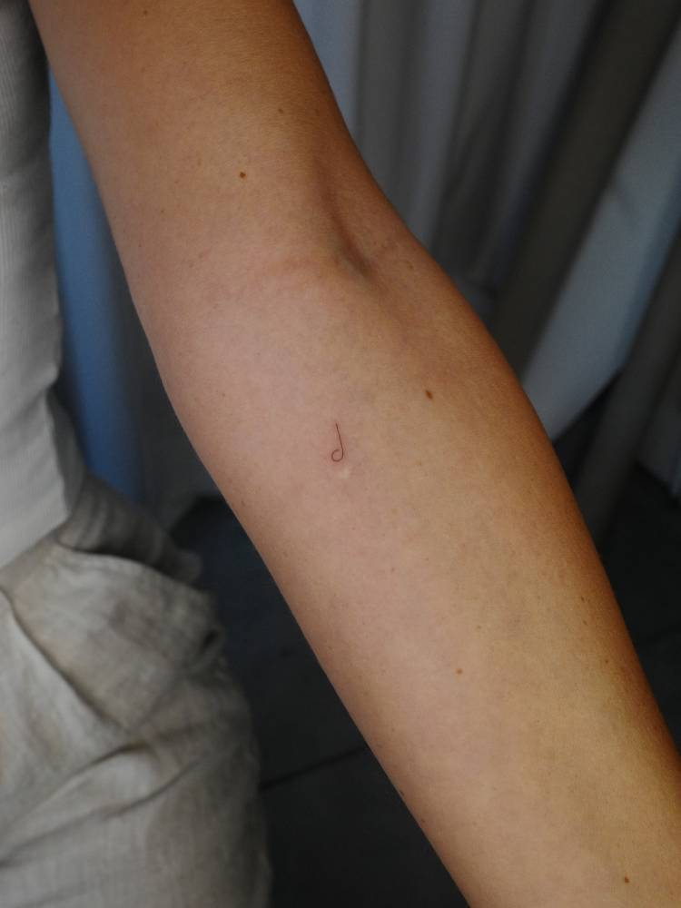 Tiny minimalistic music note tattoo located on the inner forearm.