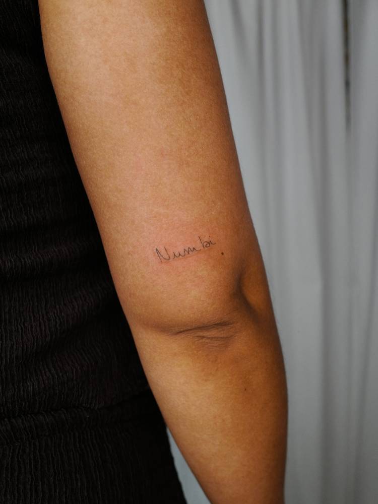 Handwritten lettering tattoo located on the wrist.