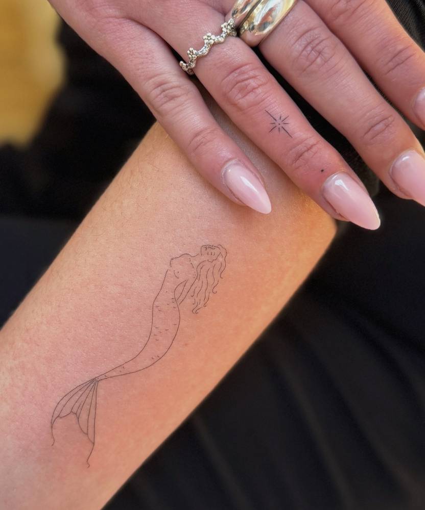Mermaid tattoo in fine line style placed on the forearm.