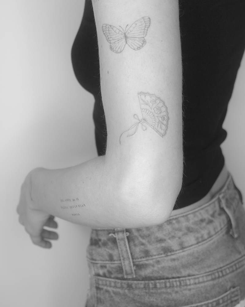 Hand fan tattoo in fine line style placed on the upper arm.