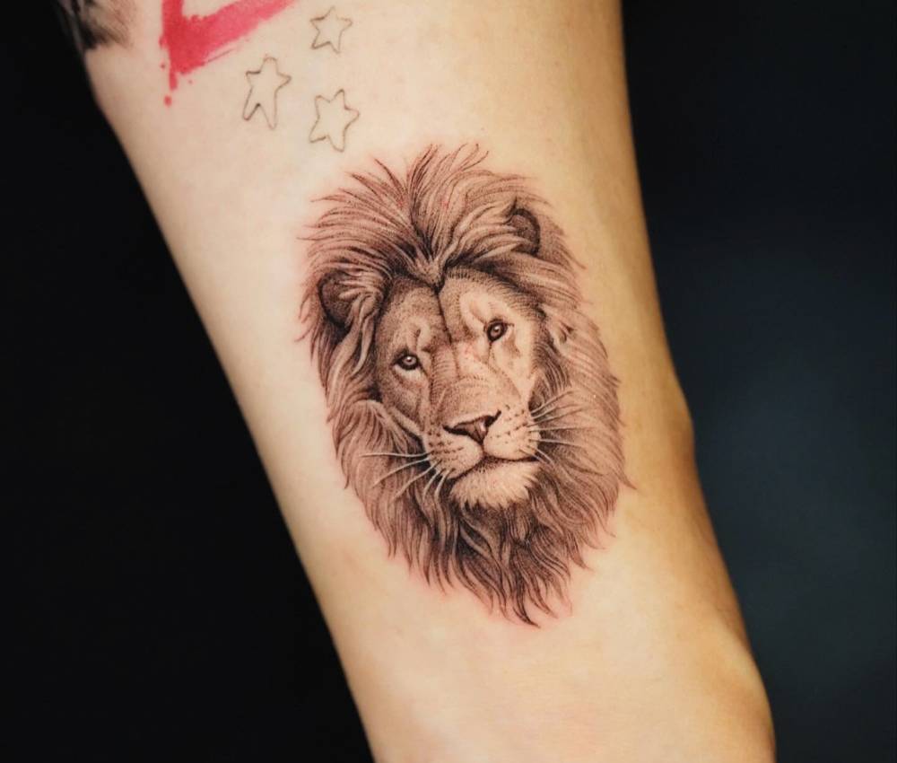 Micro-realistic style lion portrait tattoo located on the inner forearm.