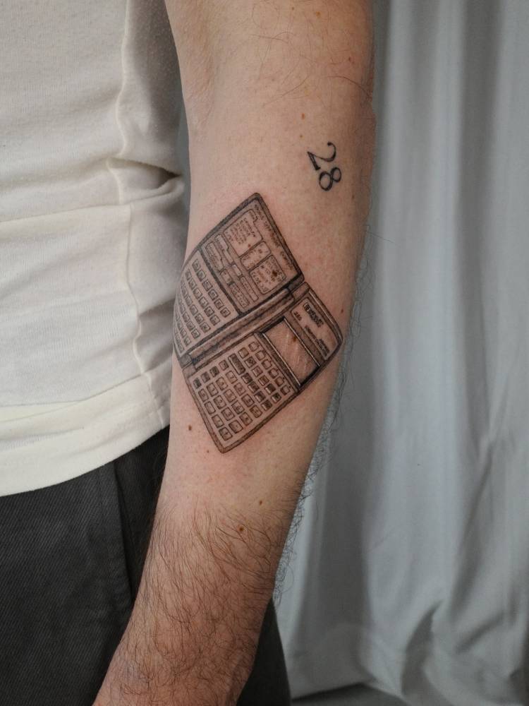 Calculator tattoo in black and grey style located on the forearm.