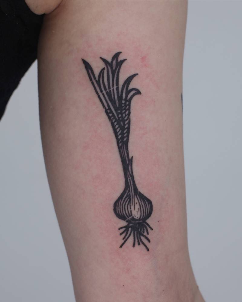 Scallion tattoo in engraving style located on the inner arm.