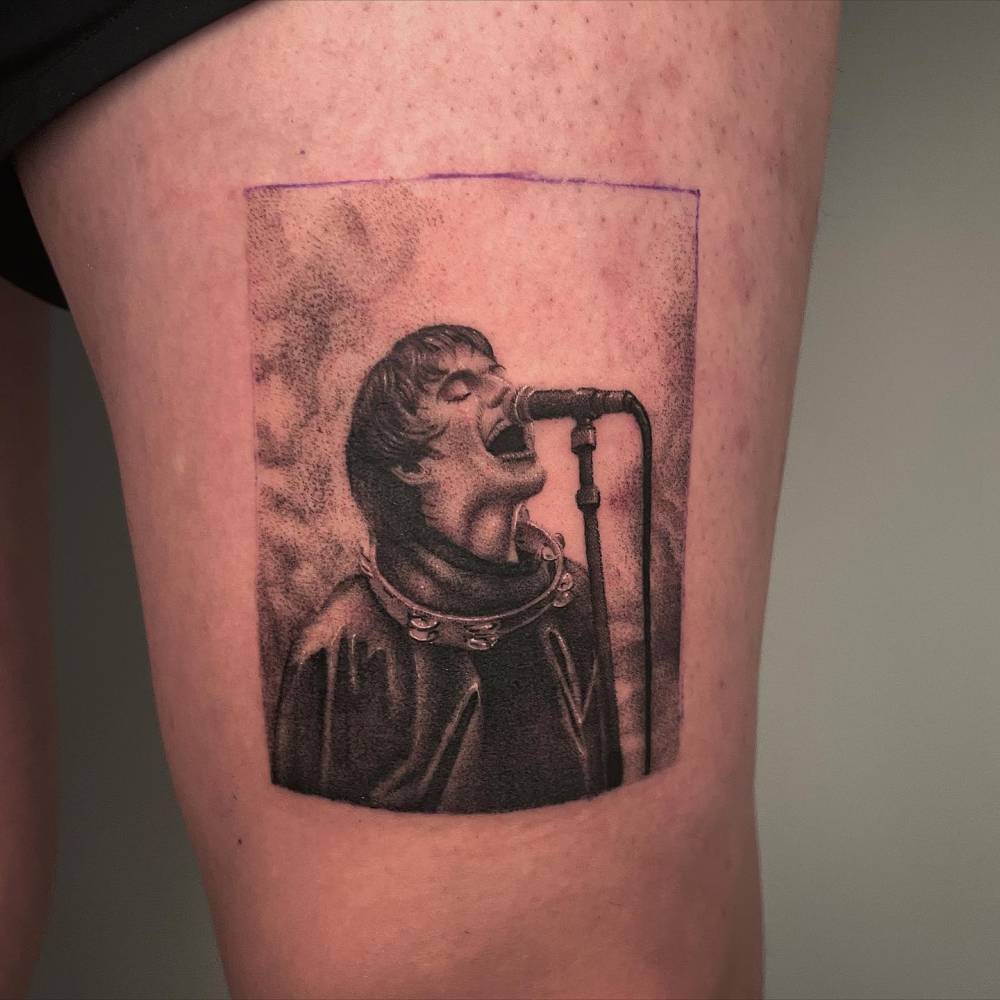 Liam Gallagher tattoo located on the thigh, black and grey style.