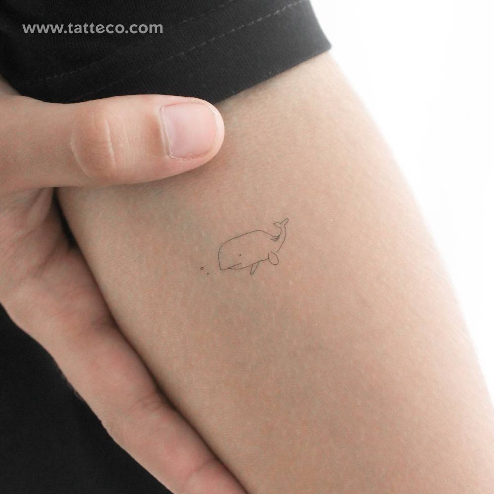 Minimalist whale temporary tattoo located on the inner forearm.