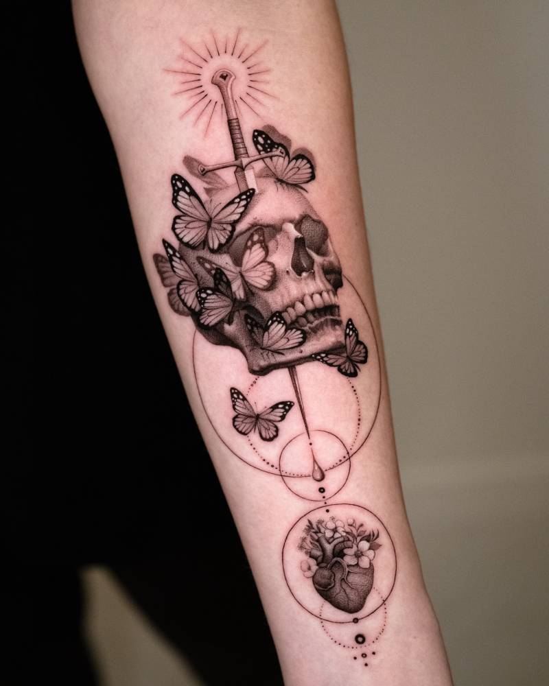 Graphic style skull and butterflies tattoo located on the inner forearm.