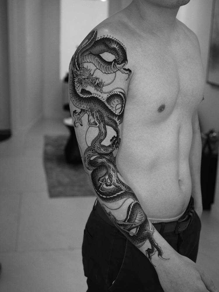 Dragons and snake battle royale tattoo located on the arm.
