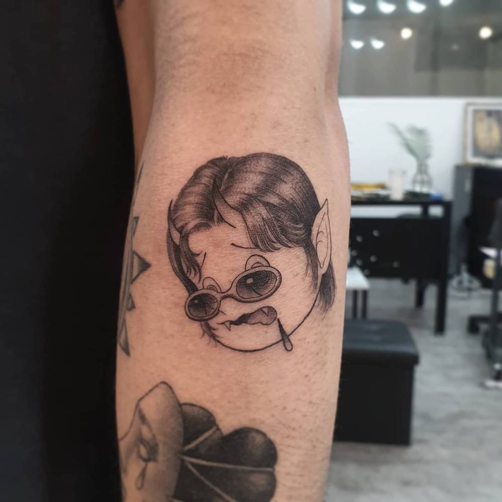 Cartoon style devil tattoo located on the forearm.