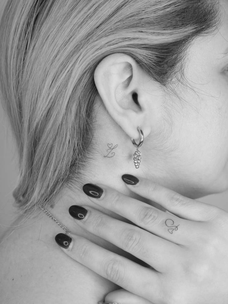 Initials "J" and "L" tattooed on the finger and behind the ear.
