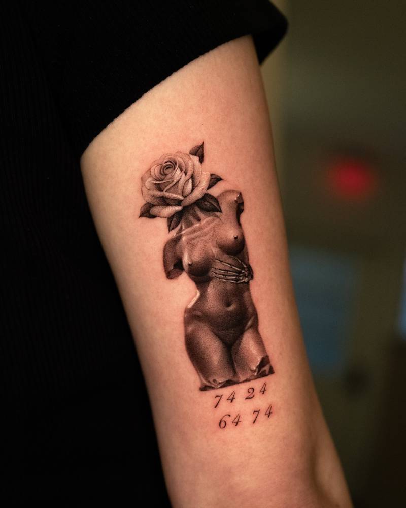 Flower head woman sculpture tattooed on the tricep, micro-realistic style.