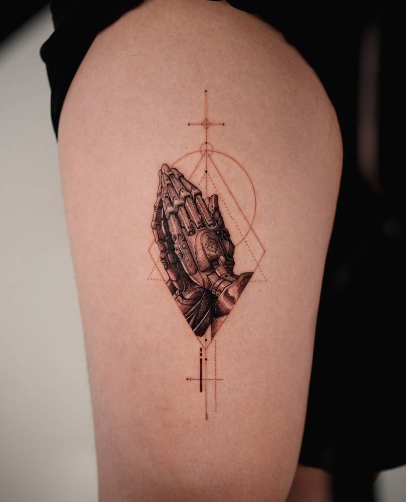 Robotic 'Praying Hands' tattoo located on the thigh.
