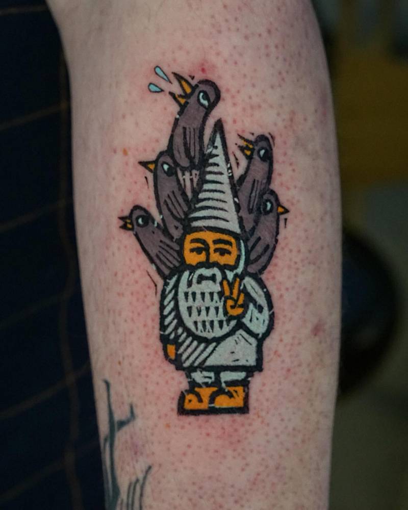 Gnome and pigeons tattoo in pop art style located on the forearm.