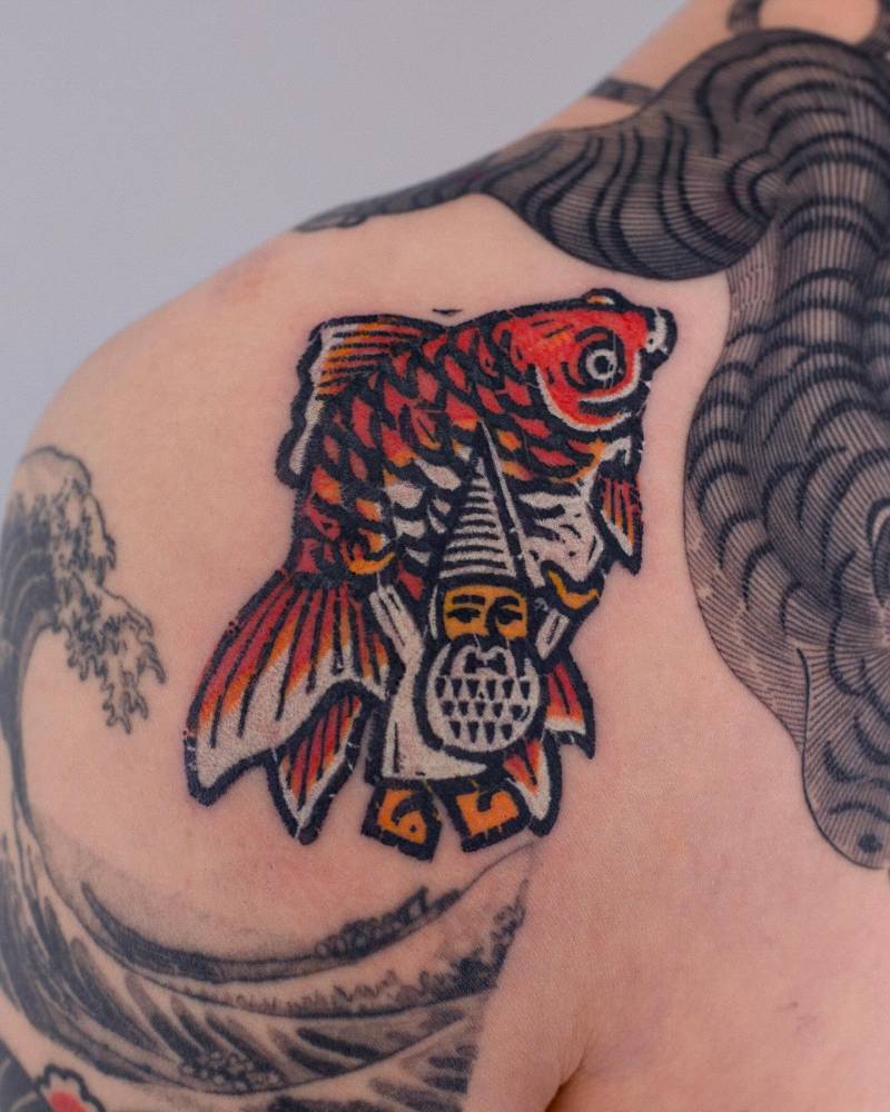 Gnome carrying a goldfish tattooed on the shoulder.