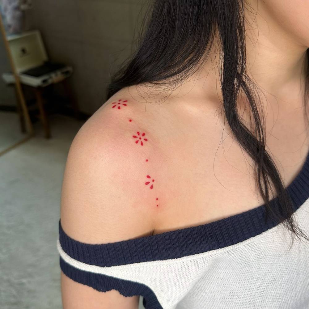 Ornamental red flowers tattoo located on the shoulder.