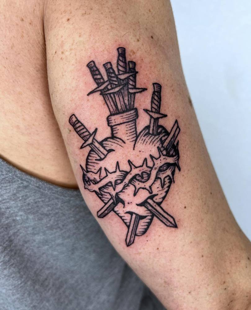 Sacred heart and swords tattoo located on the tricep.