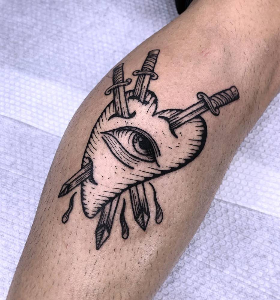 Eye heart and swords tattoo located on the calf, engraving style.