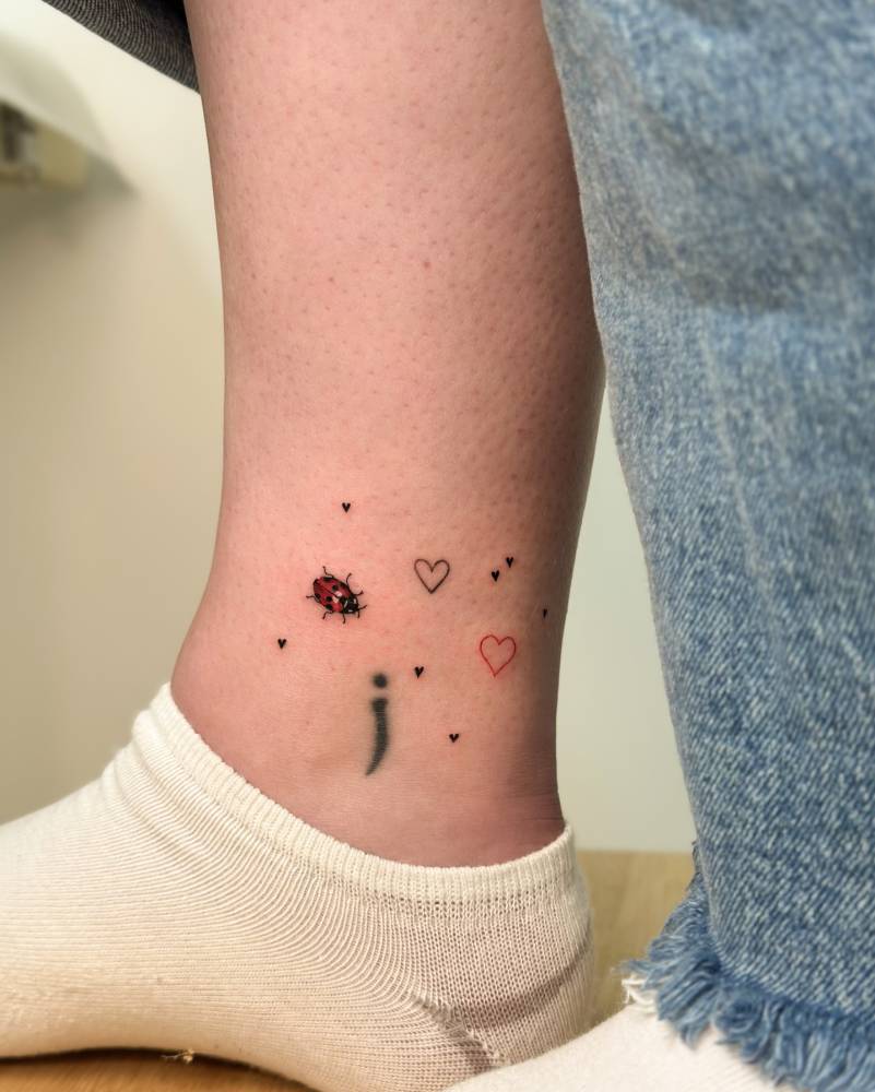 Illustrative style ladybug and hearts tattoo done on the ankle.