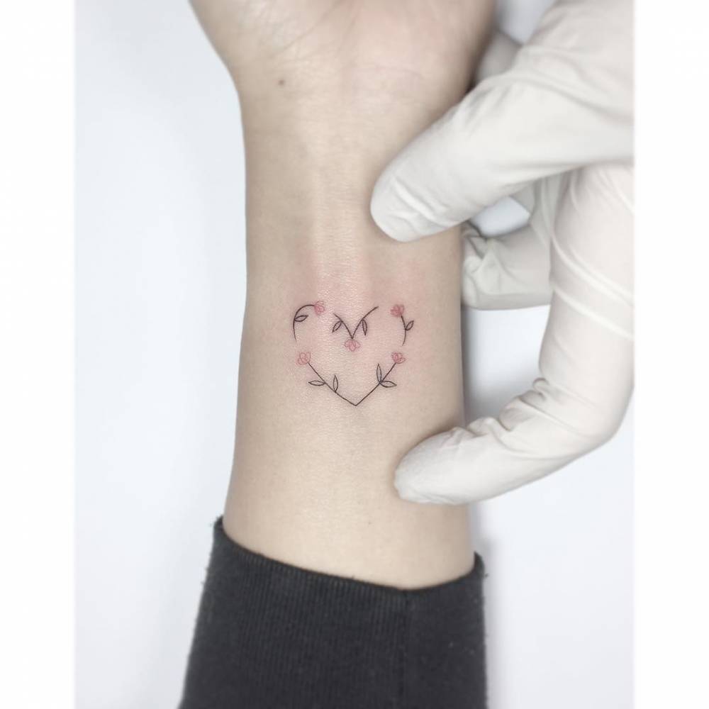 Heart flower tattoo in fine line style placed on the wrist.