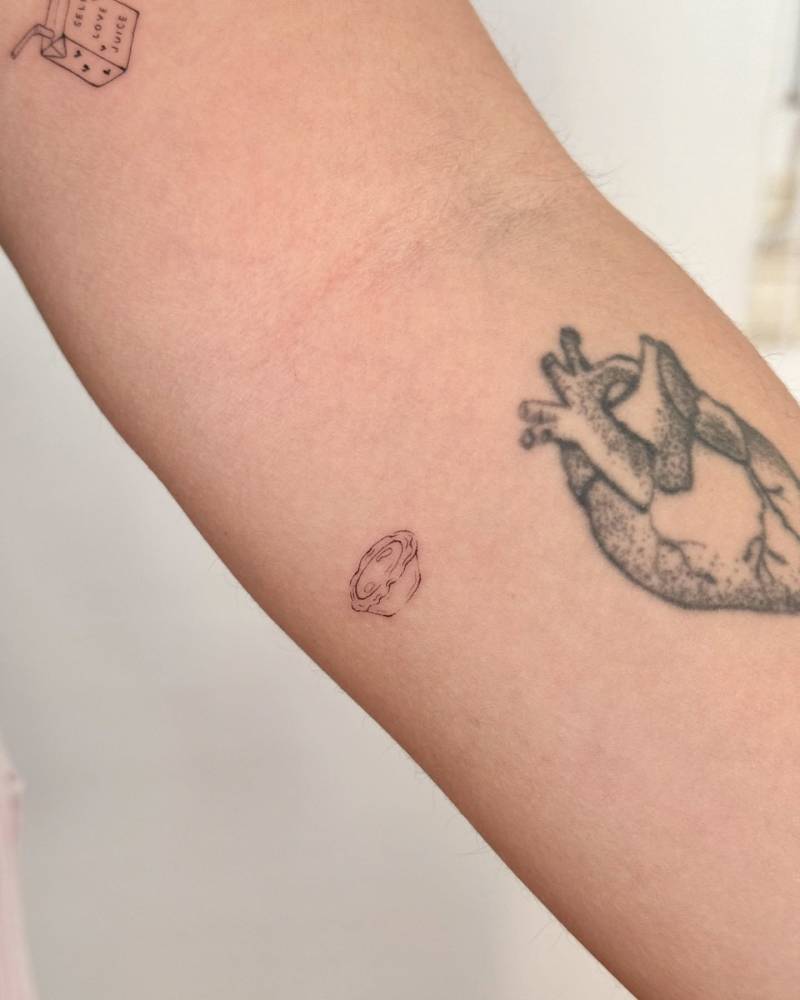 Fine line style tiny pastel de nata tattoo placed on the inner forearm.