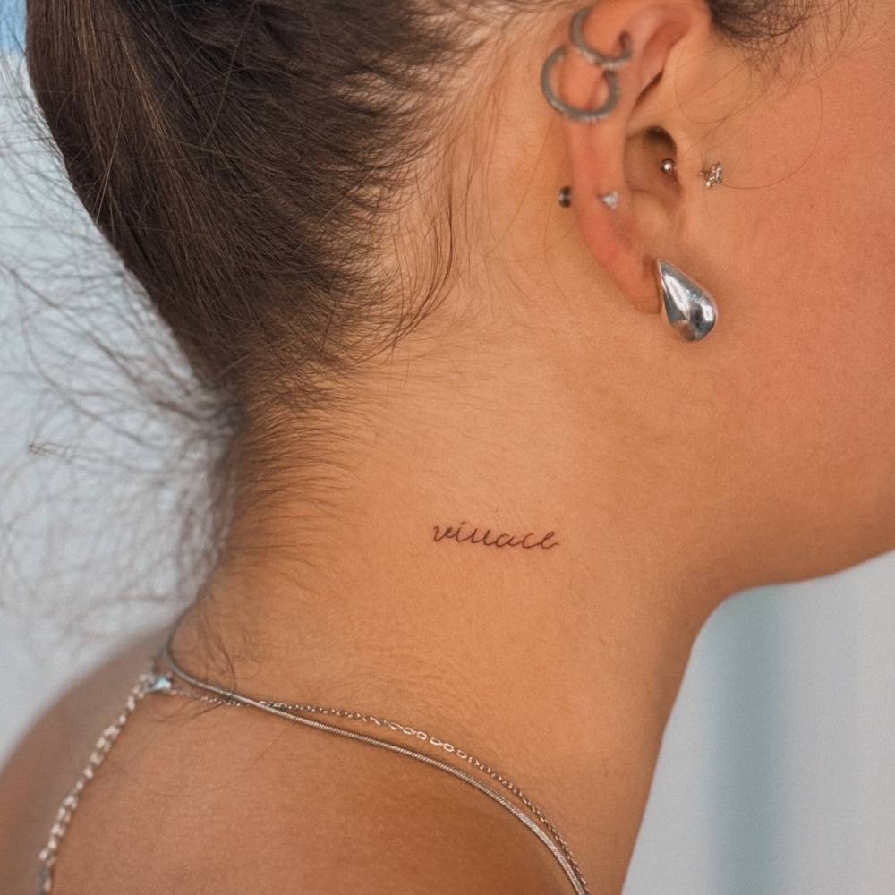 Handwritten lettering tattoo located on the neck.