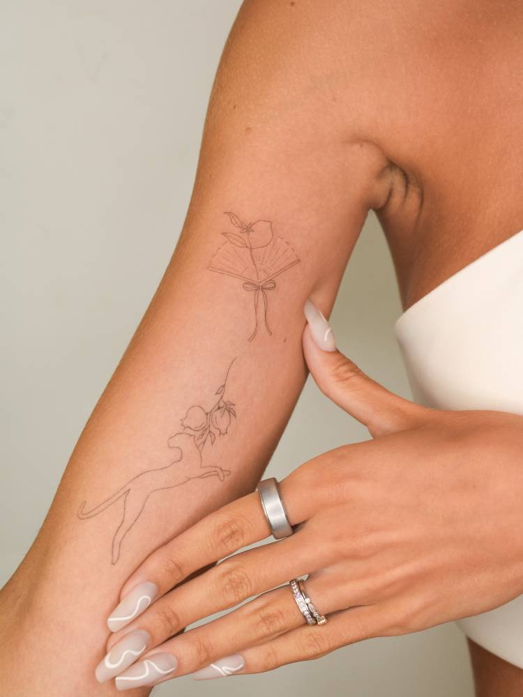 Fine line style leopard and hand fan tattoos located on the inner arm.