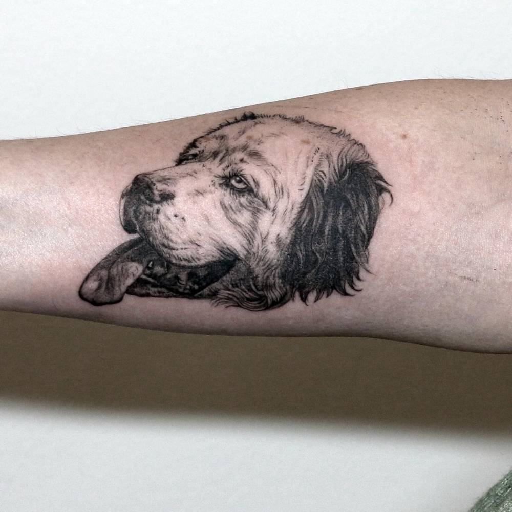 Black and grey dog portrait tattoo located on the inner forearm.