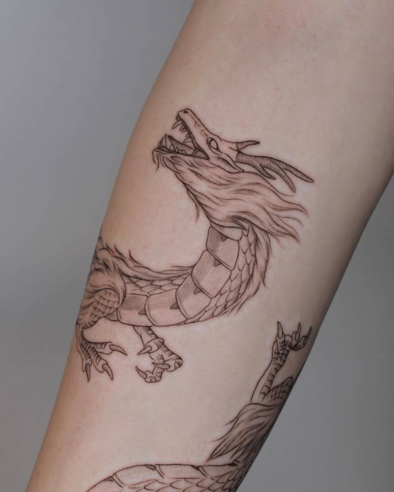 Illustrative style dragon tattoo located on the inner forearm.