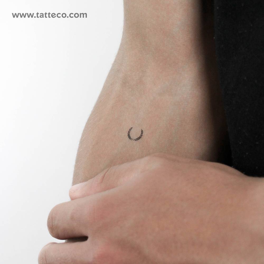 Tiny minimalistic laurel wreath temporary tattoo located on the inner forearm.