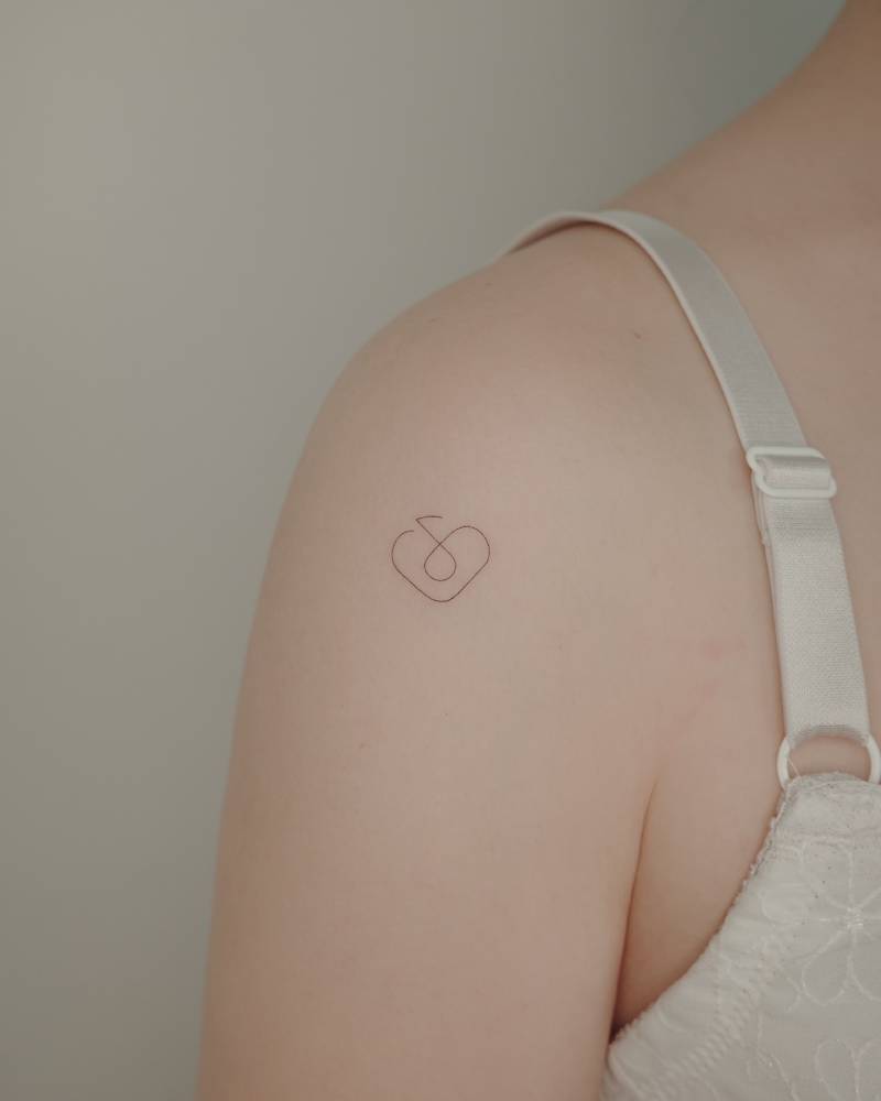 Fine line style quaver and heart tattoo located on the shoulder.