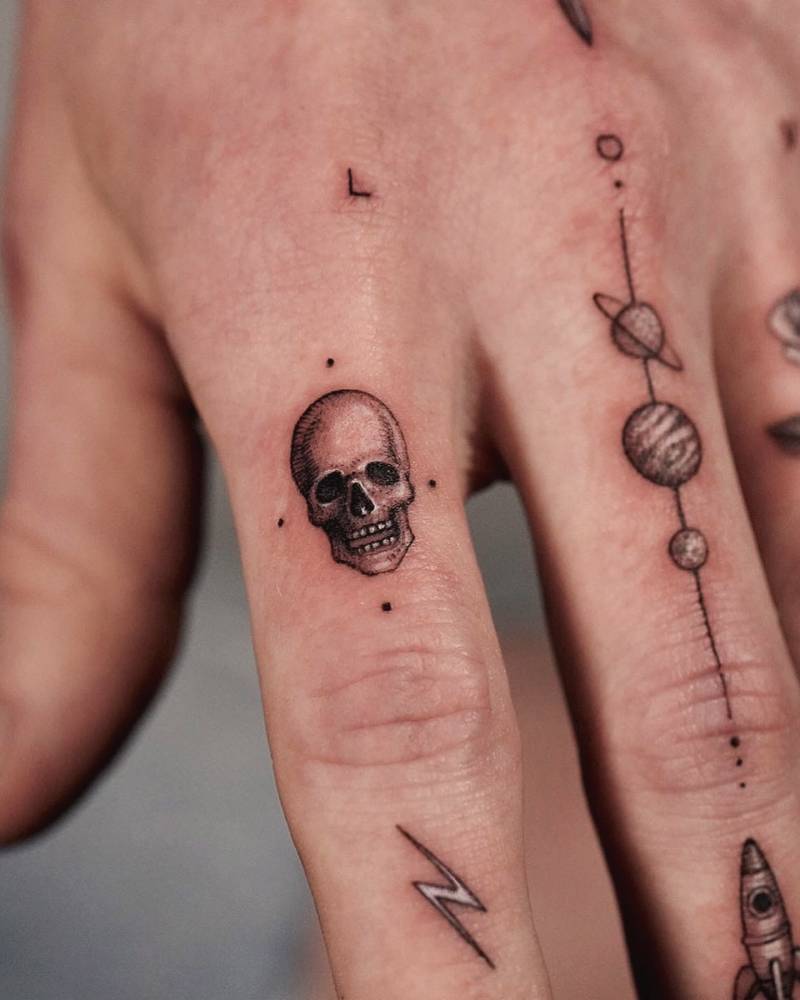 Tiny single skull tattoo located on the finger.
