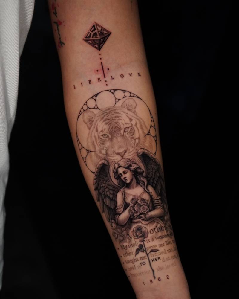 Graphic style angel and tiger tattoo located on the inner forearm.
