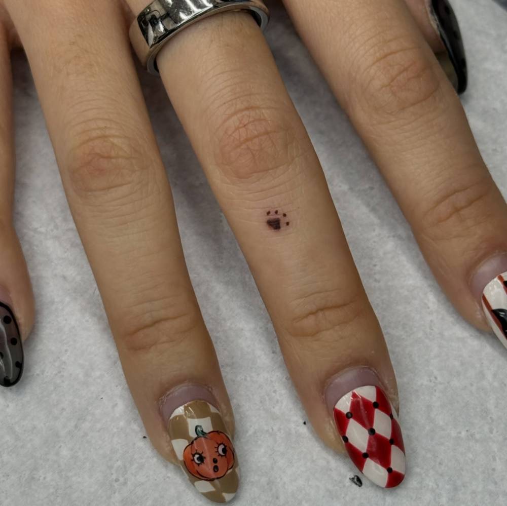 Tiny minimalistic paw print tattoo located on the finger.