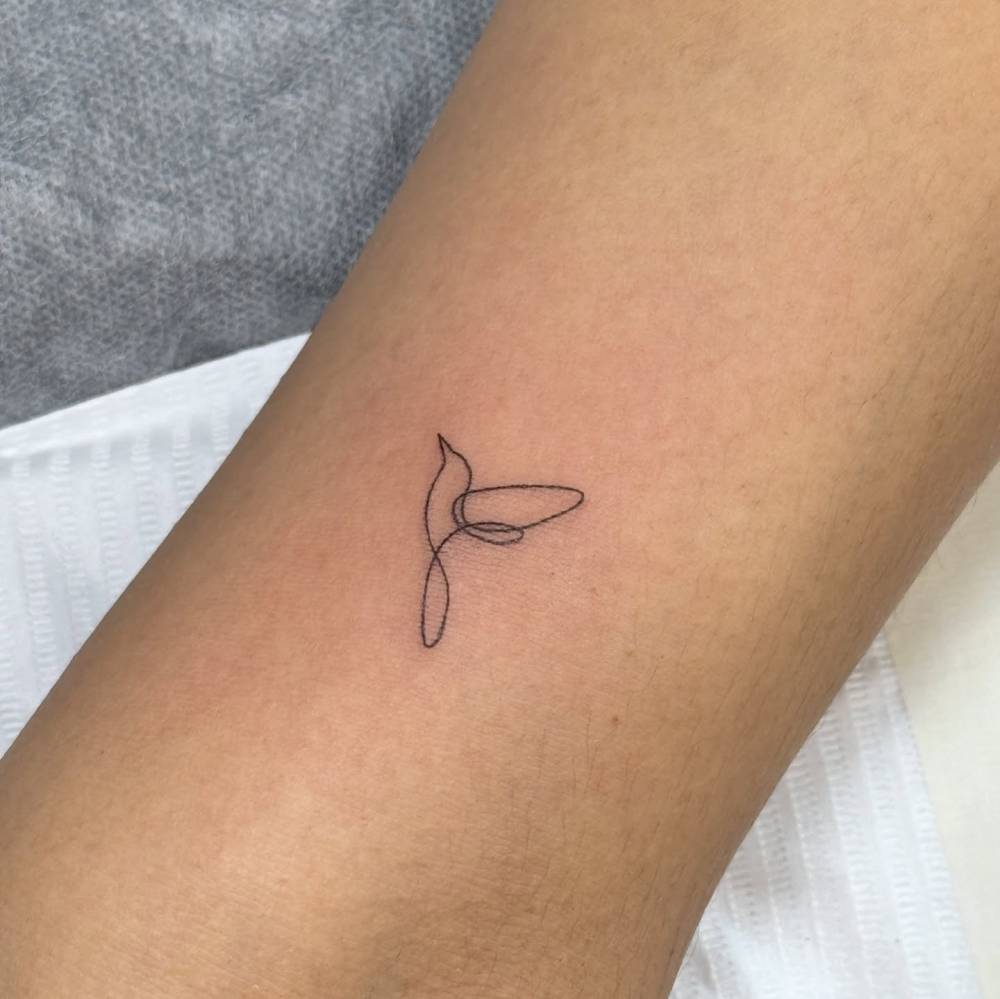 One line hummingbird tattoo located on the inner arm.