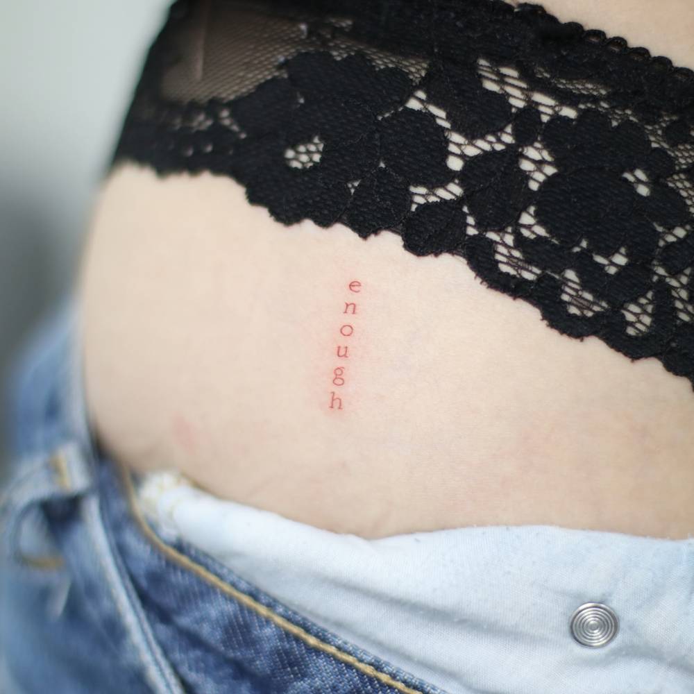 Word "enough" in typewriter font tattooed on the hip.