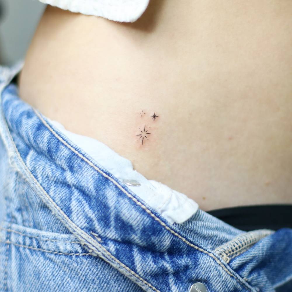 Sparkling stars tattoo in minimalistic style located on the hip.