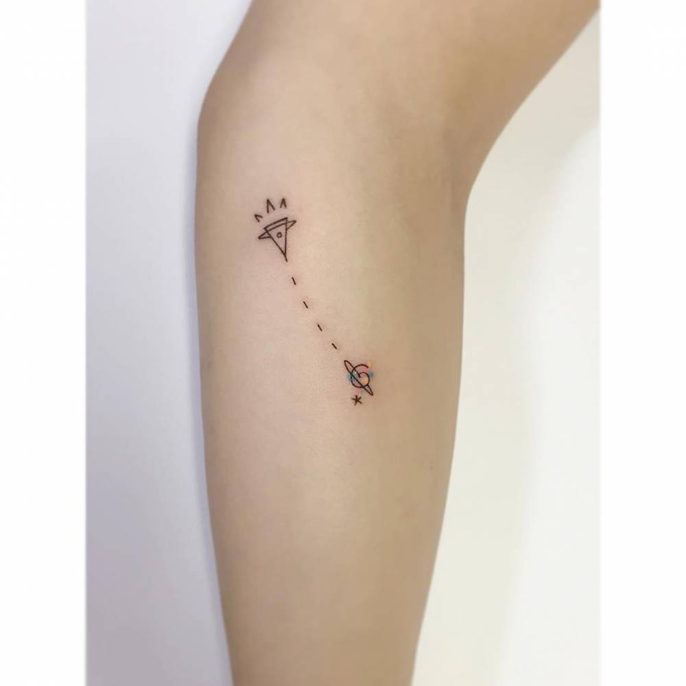 Minimalistic style rocket to Saturn tattoo placed on the forearm.