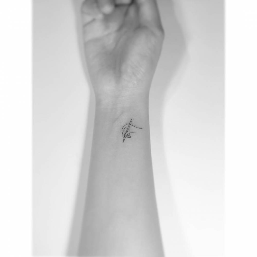 Hand and pencil tattoo in minimalistic style, placed on the wrist.
