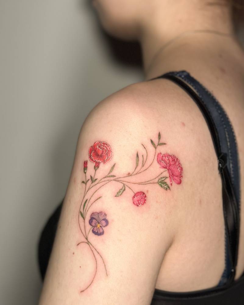 Watercolor style flowers tattooed on the shoulder.