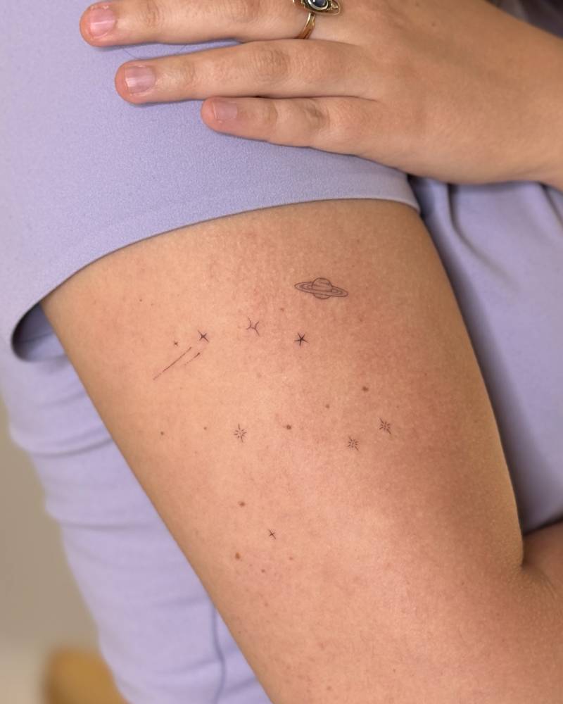 Minimalistic style galaxy tattoo located on the upper arm.
