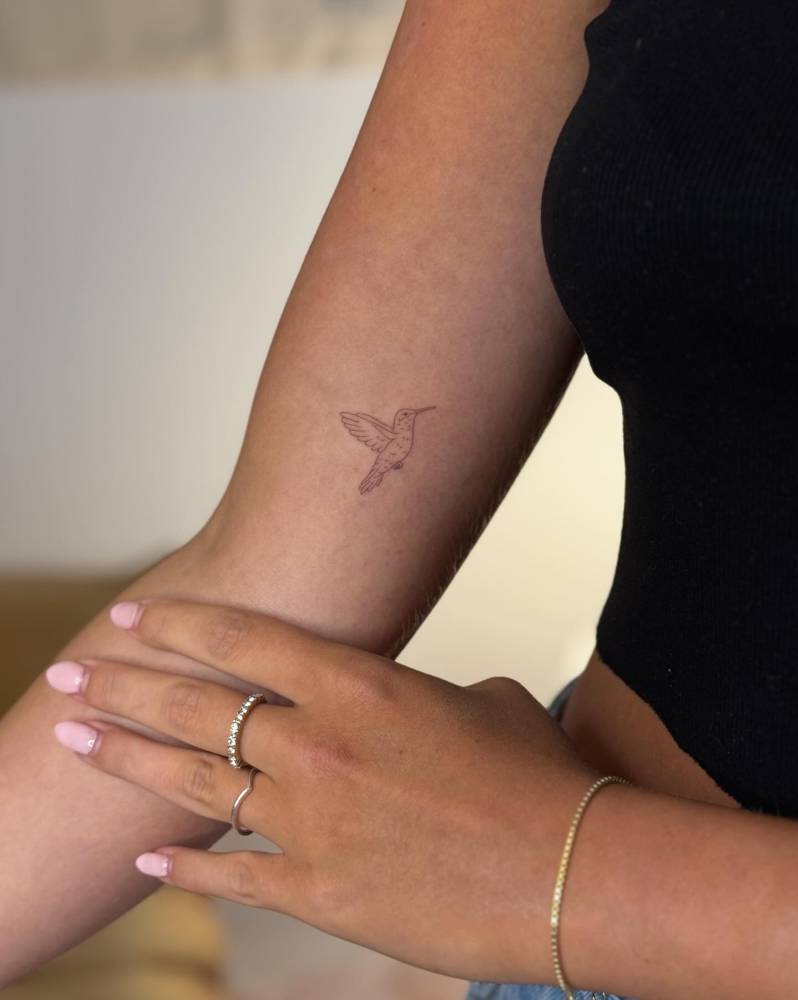 Little hummingbird tattoo placed on the inner arm, fine line style.