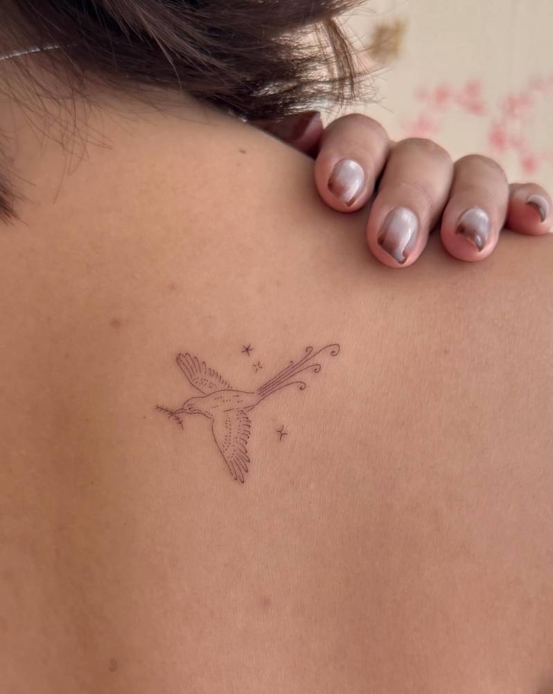 Fine line style dove tattooed on the upper back.