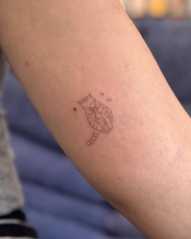 Cute cat tattoo located on the inner arm, done in fine line style.