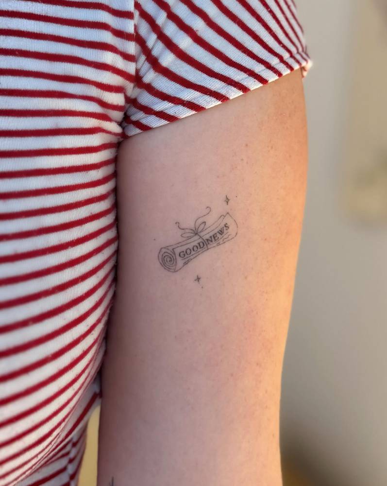 Healed fine line style newspaper tattoo located on the bicep.