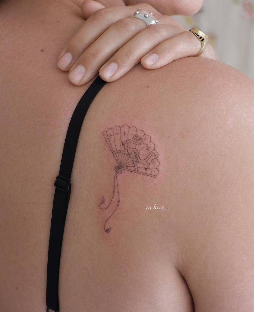 Hand fan tattoo located on the shoulder blade, fine line style.