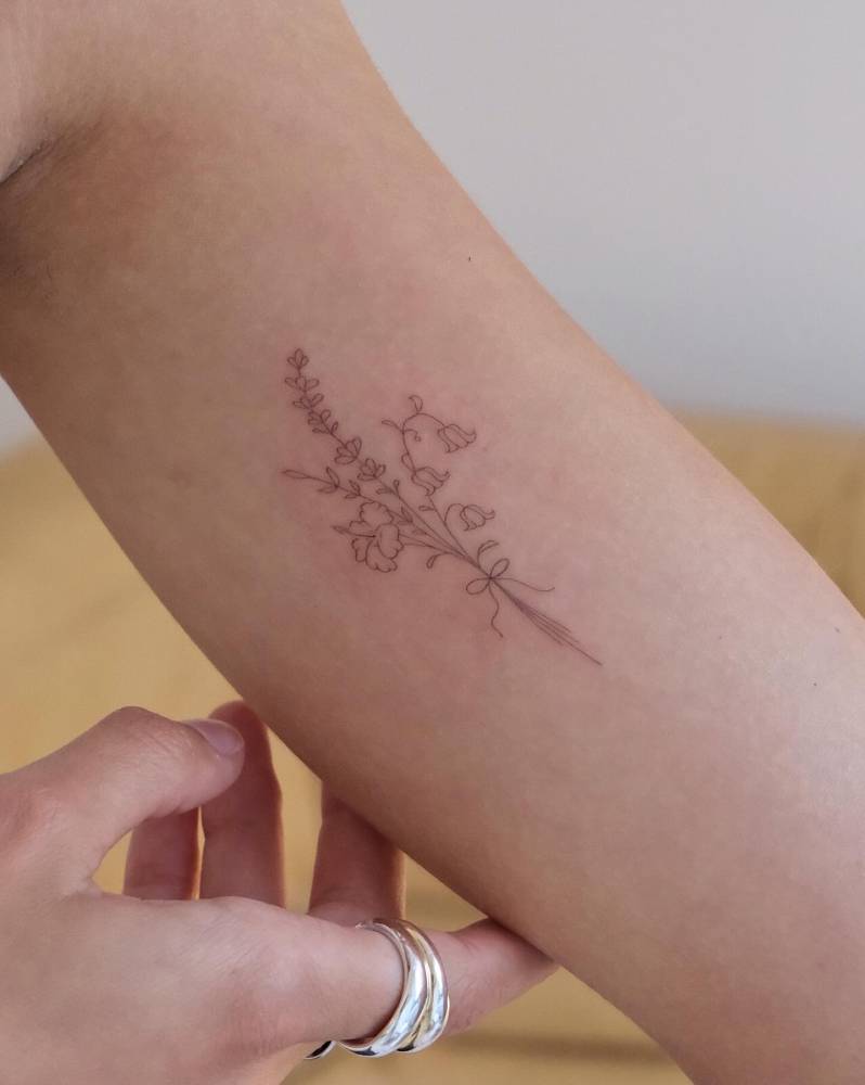 Flower bouquet tattoo placed on the inner arm, fine line style.