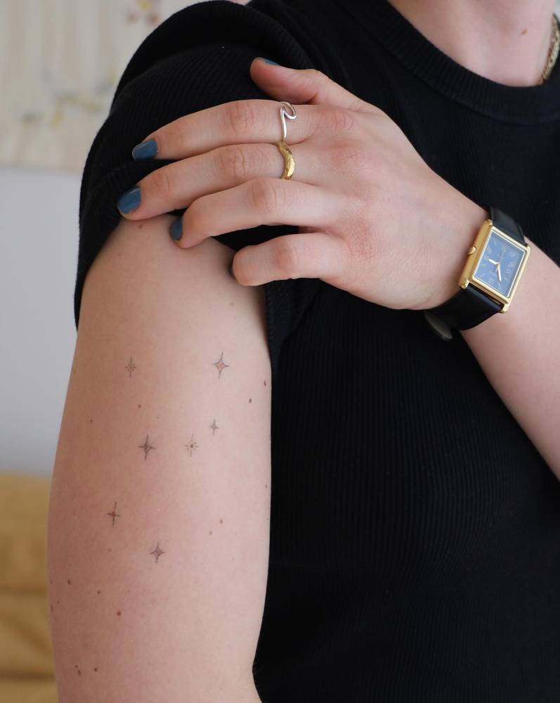 Healed sparkling stars tattoo located on the upper arm.